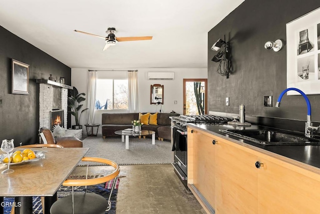 kitchen with stainless steel range with gas stovetop, sink, a fireplace, dark colored carpet, and a wall mounted AC