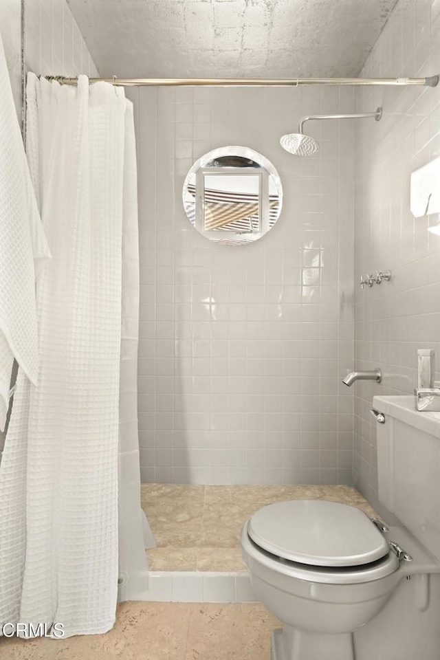 full bath with toilet, tile walls, a shower stall, and tile patterned flooring