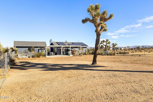 back of property featuring roof mounted solar panels, a chimney, a patio, and fence