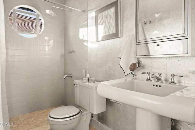 bathroom with toilet, tasteful backsplash, a tile shower, and a sink