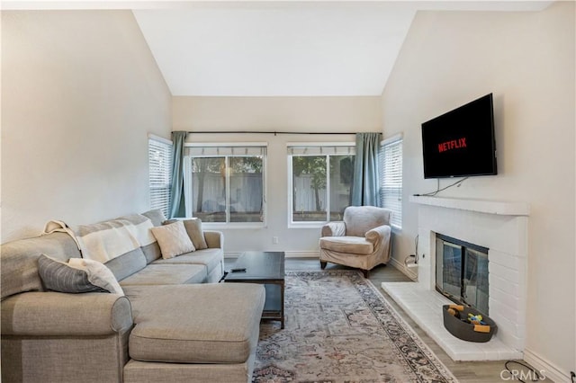 living room with hardwood / wood-style flooring, a fireplace, and lofted ceiling