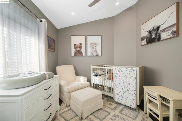 bedroom with ceiling fan, vaulted ceiling, and a crib