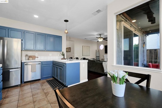 kitchen with pendant lighting, blue cabinets, ceiling fan, kitchen peninsula, and stainless steel appliances