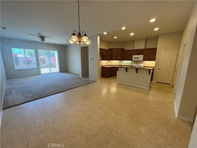 kitchen with a center island, range, pendant lighting, ceiling fan with notable chandelier, and a breakfast bar area