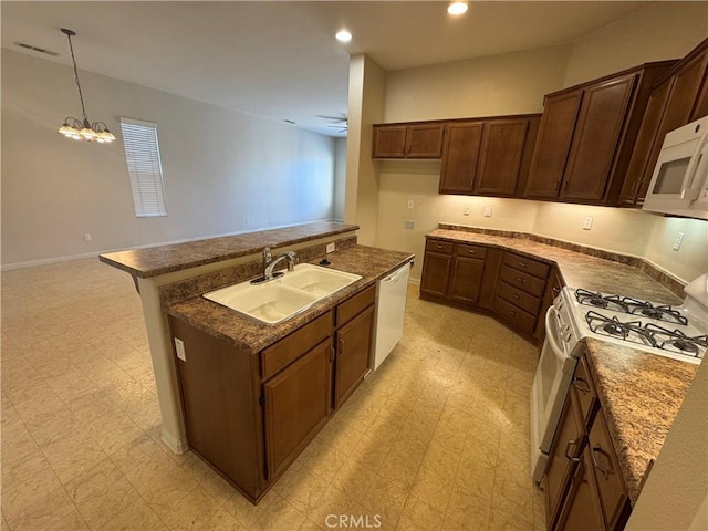 kitchen with white appliances, a kitchen island with sink, sink, pendant lighting, and ceiling fan with notable chandelier