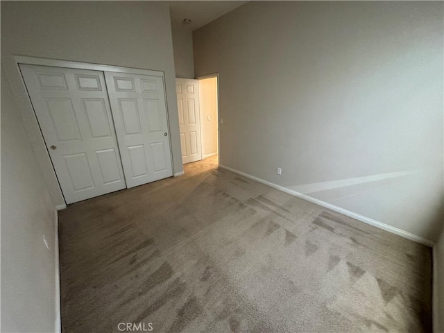 unfurnished bedroom with carpet floors, a high ceiling, and a closet