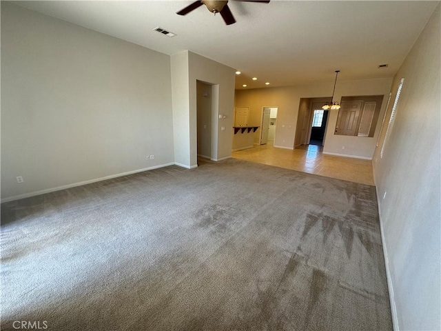 unfurnished living room with ceiling fan with notable chandelier and light colored carpet