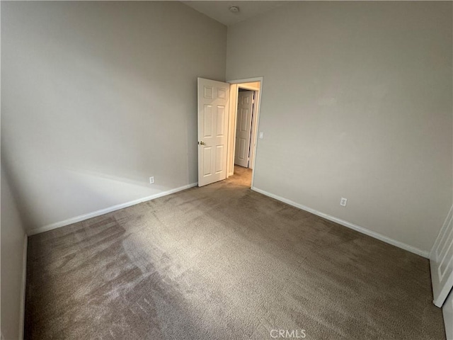 unfurnished room with a towering ceiling and dark carpet