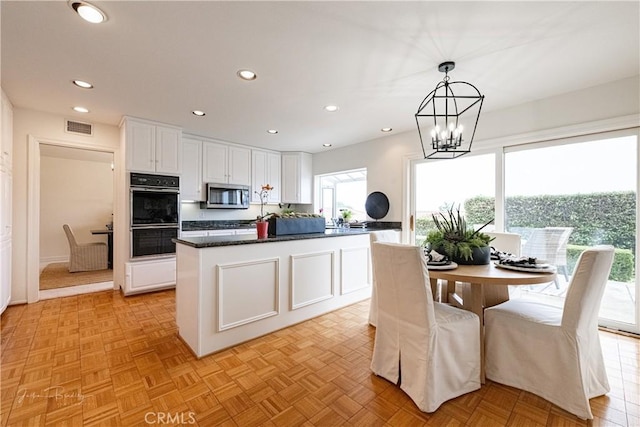 kitchen featuring double oven, decorative light fixtures, light parquet flooring, and white cabinets