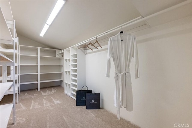 walk in closet with vaulted ceiling and carpet flooring