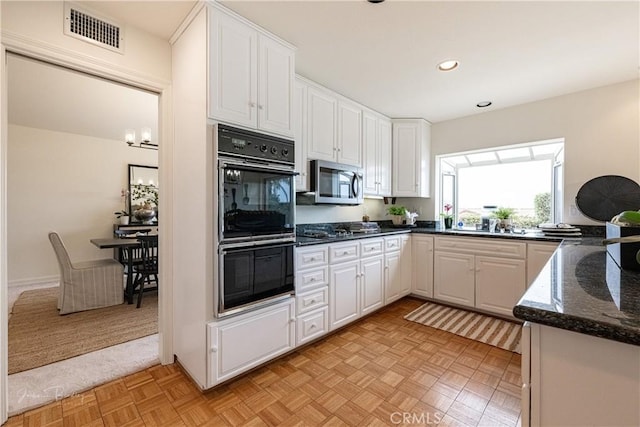 kitchen featuring white cabinetry, stainless steel appliances, dark stone counters, and light parquet floors