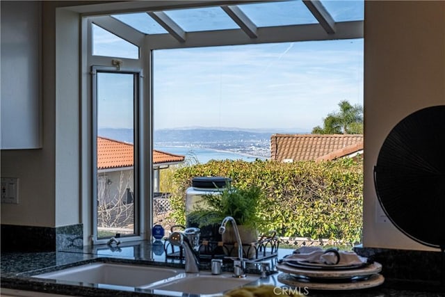 interior space with sink, stone counters, and a water view