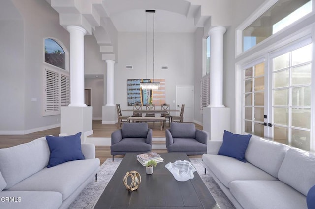 living room with decorative columns, a high ceiling, and hardwood / wood-style floors