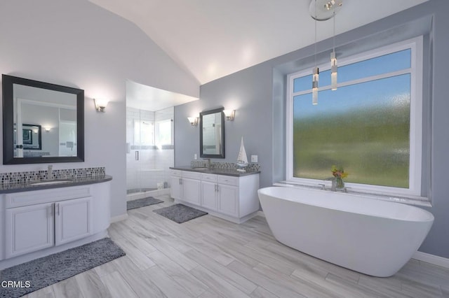 bathroom with lofted ceiling, hardwood / wood-style flooring, vanity, decorative backsplash, and a tub