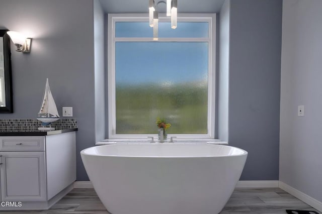 bathroom featuring hardwood / wood-style floors, vanity, a washtub, and backsplash