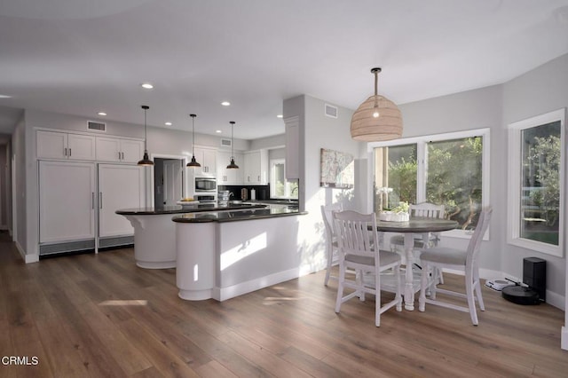 kitchen featuring white cabinetry, dark hardwood / wood-style floors, a center island, and pendant lighting