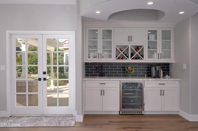 bar with sink, white cabinetry, wood-type flooring, decorative backsplash, and beverage cooler