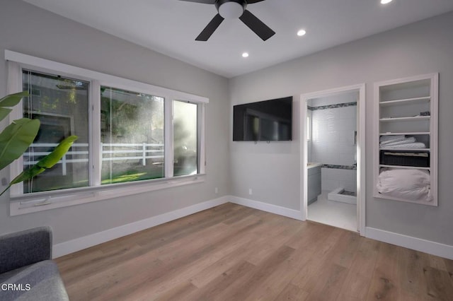 unfurnished bedroom featuring multiple windows, light hardwood / wood-style flooring, ceiling fan, and ensuite bath