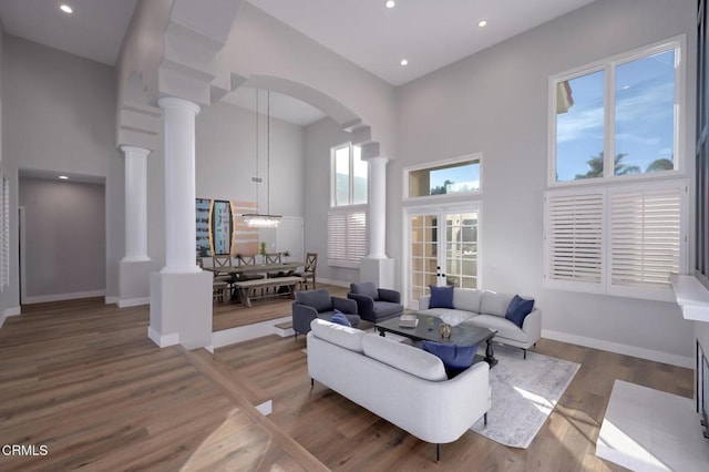 living room featuring decorative columns, wood-type flooring, and a high ceiling