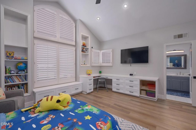 bedroom featuring ceiling fan, lofted ceiling, connected bathroom, and built in desk