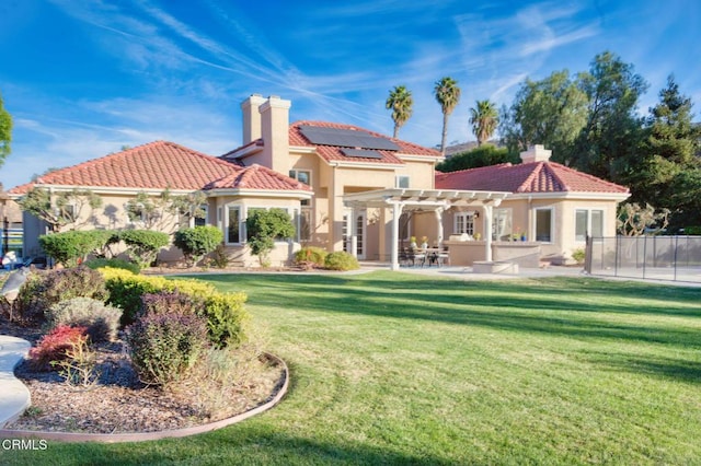 rear view of property with a pergola, a lawn, a patio, and solar panels