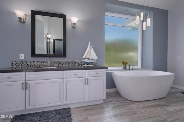 2021 Brittany Park Rd, Camarillo, CA 93012 - full bathroom with wood finished floors, vanity, backsplash, a soaking tub, and baseboards