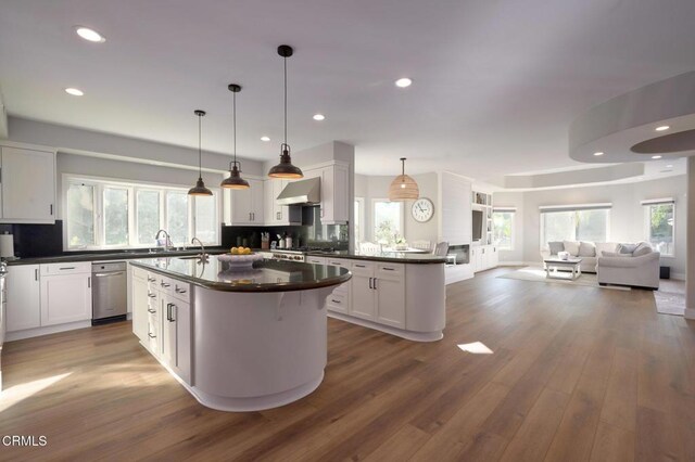 2021 Brittany Park Rd, Camarillo, CA 93012 - kitchen featuring dark countertops, open floor plan, white cabinetry, wall chimney range hood, and tasteful backsplash