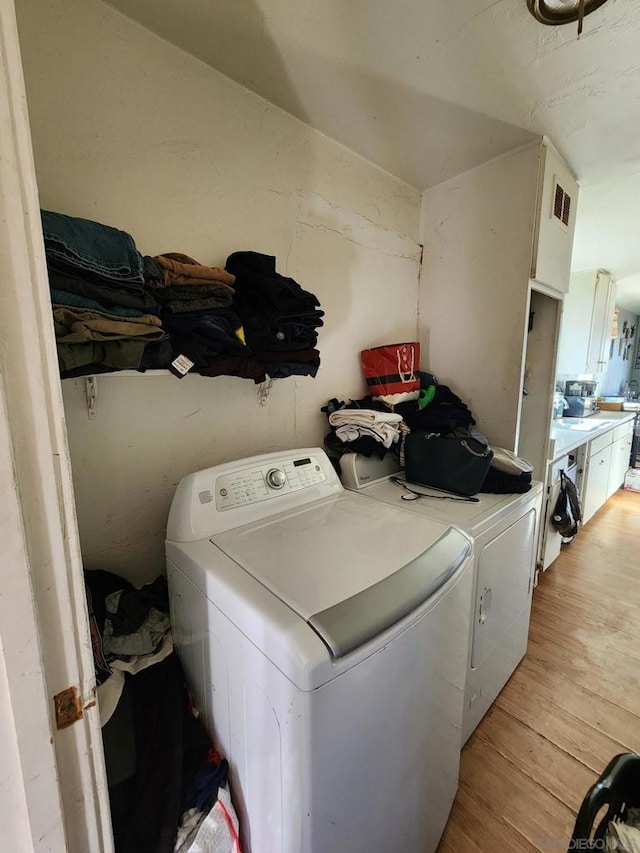 washroom with separate washer and dryer and light hardwood / wood-style flooring