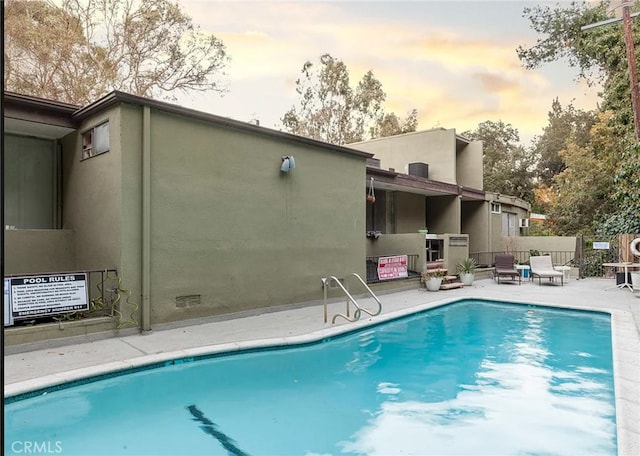 pool at dusk featuring a patio area