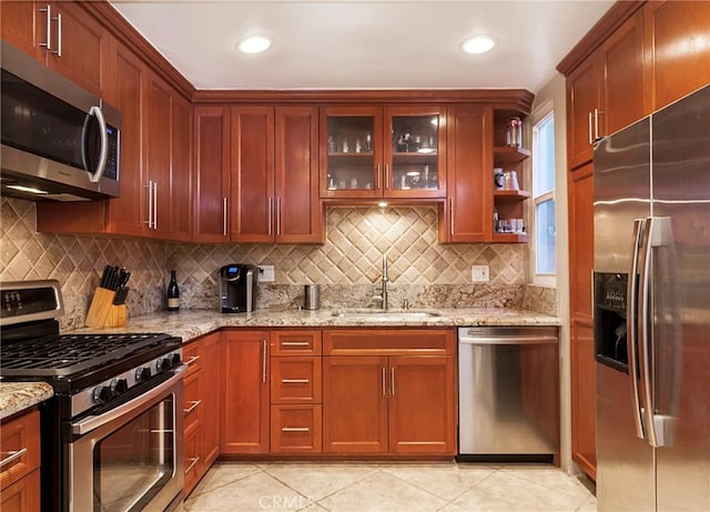 kitchen with sink, tasteful backsplash, light tile patterned floors, light stone countertops, and stainless steel appliances