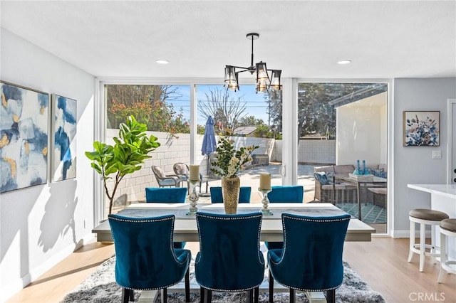 dining area with a healthy amount of sunlight, a wall of windows, a notable chandelier, and light hardwood / wood-style floors