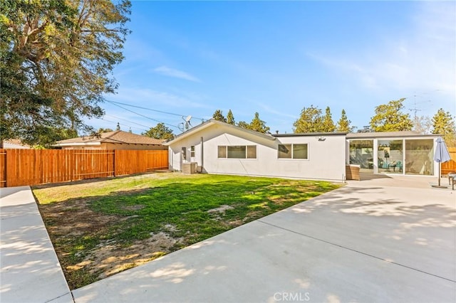 back of property featuring a patio area, a lawn, and a sunroom