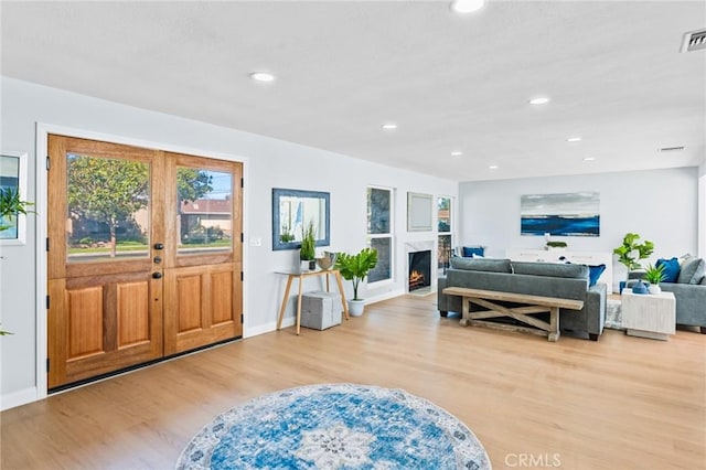 entrance foyer featuring a premium fireplace, french doors, and light hardwood / wood-style flooring