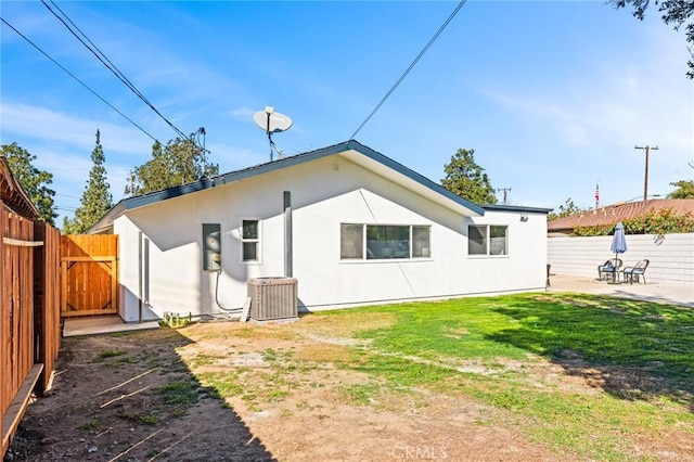 back of property featuring a lawn, a patio area, and central AC