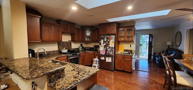 kitchen with fridge, kitchen peninsula, stainless steel stove, and a skylight