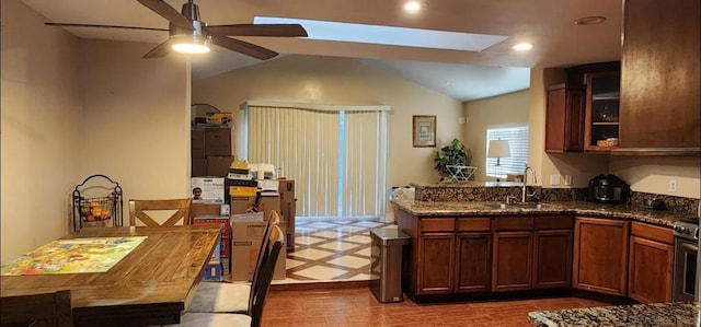 kitchen featuring dark hardwood / wood-style floors, lofted ceiling, sink, dark stone countertops, and ceiling fan