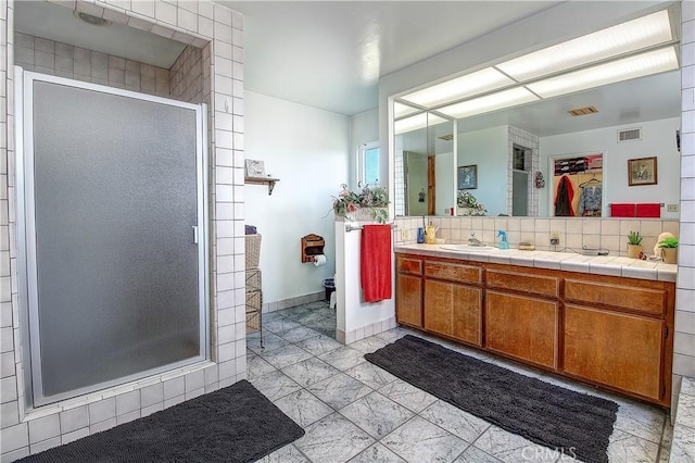 bathroom with vanity, a shower with shower door, and backsplash