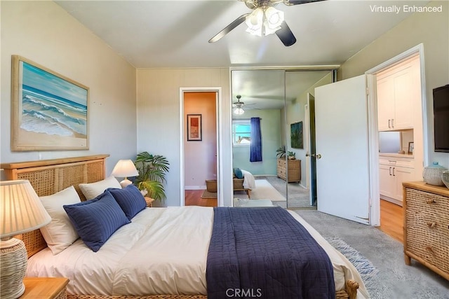 bedroom with light carpet, ensuite bath, a closet, and ceiling fan