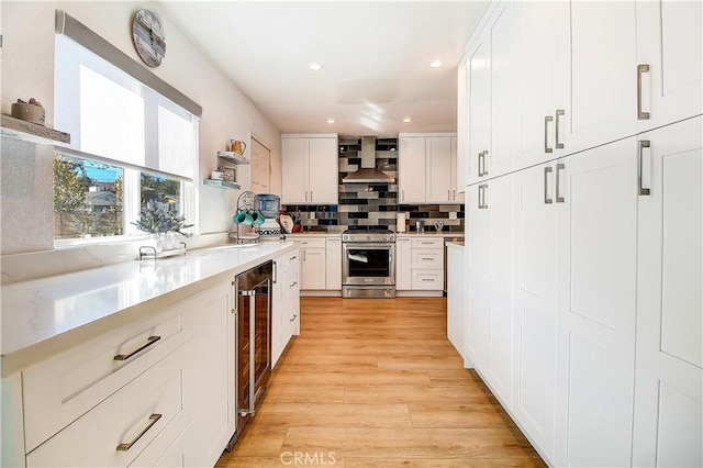 kitchen with white cabinetry, wine cooler, decorative backsplash, stainless steel gas range oven, and light hardwood / wood-style flooring