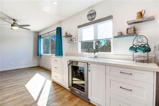 bar with wine cooler, white cabinetry, and light hardwood / wood-style flooring