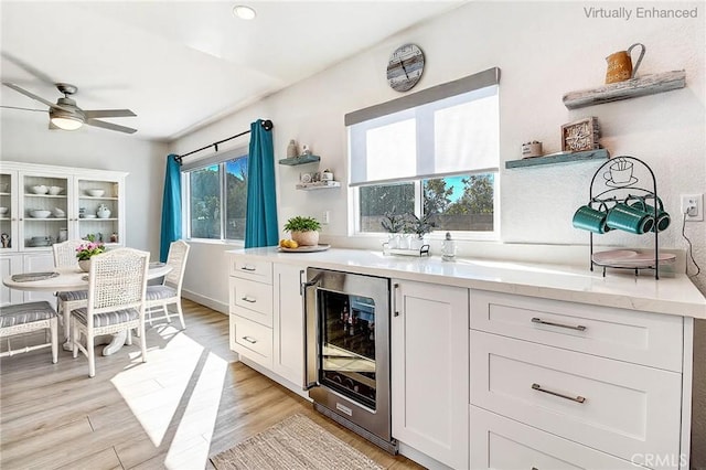 kitchen featuring wine cooler, ceiling fan, light hardwood / wood-style flooring, and white cabinets