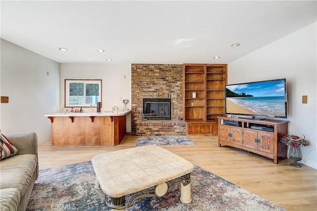 living room with a brick fireplace, built in features, and light wood-type flooring