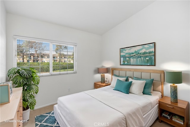 carpeted bedroom featuring baseboards and lofted ceiling