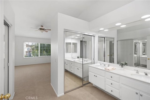 bathroom with a sink, recessed lighting, double vanity, baseboards, and ceiling fan