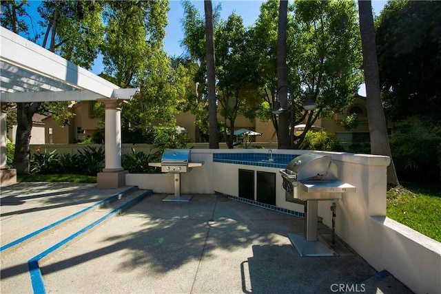 exterior space with grilling area, an outdoor kitchen, and a pergola