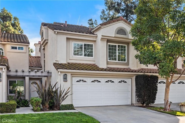 view of front of home with stucco siding, an attached garage, driveway, and a tiled roof