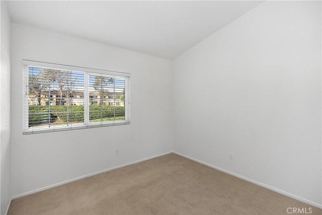 spare room featuring baseboards and light carpet