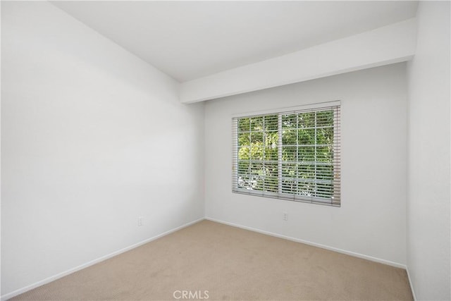 spare room featuring light colored carpet and baseboards