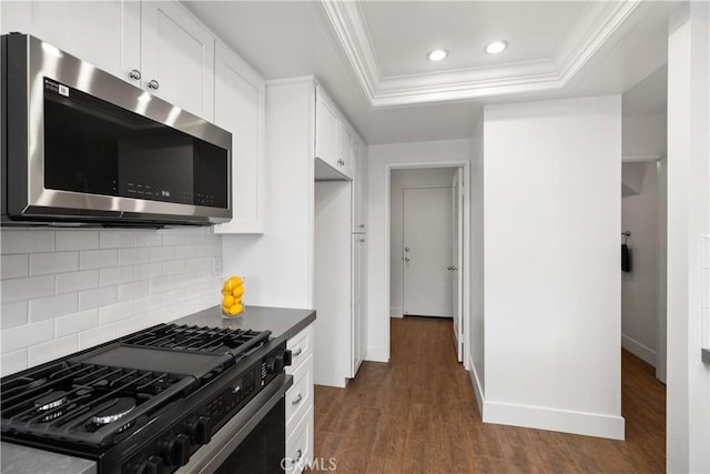 kitchen with gas stove, dark wood-type flooring, crown molding, stainless steel microwave, and a raised ceiling