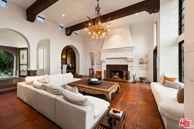 living room with a notable chandelier, a towering ceiling, beam ceiling, and a fireplace